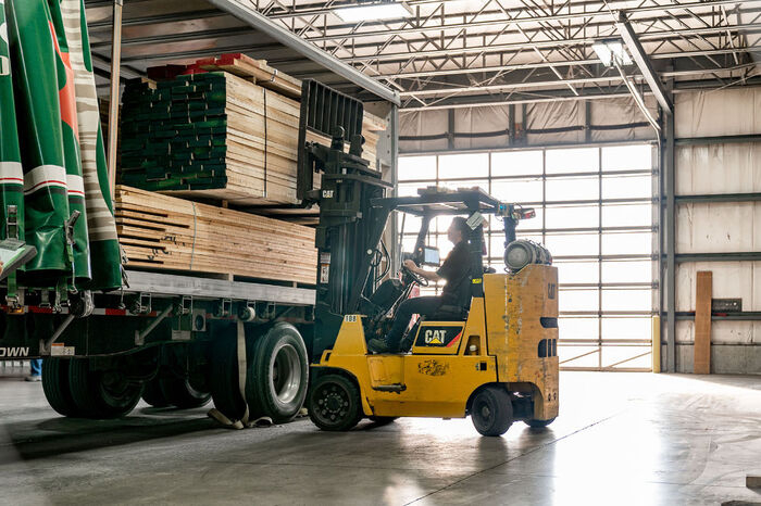 Forklift in warehouse lifting wooden products